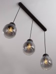 Lampa wisząca Moche z trzema kloszami w kształcie kul, wykonana z przezroczystego szkła w odcieniu szaro-czarnym. Montaż na czarnej, prostokątnej podstawie, zwisająca na cienkich czarnych przewodach. Oświetlenie E27, nowoczesny design.
