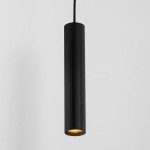Lampa wisząca Nazca w kolorze czarnym, o cylindrycznym kształcie, z metalowym wykończeniem. Zawieszona na cienkim przewodzie, z widocznym źródłem światła GU10 u dołu. Tło w jasnym kolorze, podkreślające minimalistyczny design.