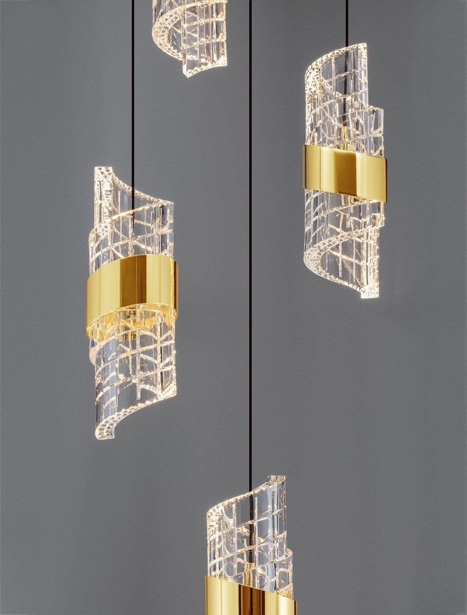 Lampa wisząca Paita z pięcioma źródłami LED, 41W, w kolorze czarnym. Składa się z przezroczystych, falowanych elementów z dekoracyjnymi złotymi obręczami. Zawieszona na cienkich linkach, tworzy nowoczesny efekt świetlny na szarym tle.