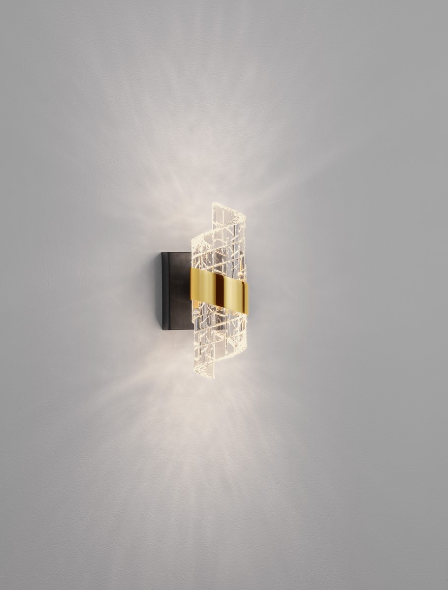 Kinkiet Paita 1xLED 9W w kolorze czarnym, z przezroczystym kloszem o geometrycznym wzorze i złotym akcentem. Zamontowany na ścianie, emitujący ciepłe światło z efektownym rozproszeniem.