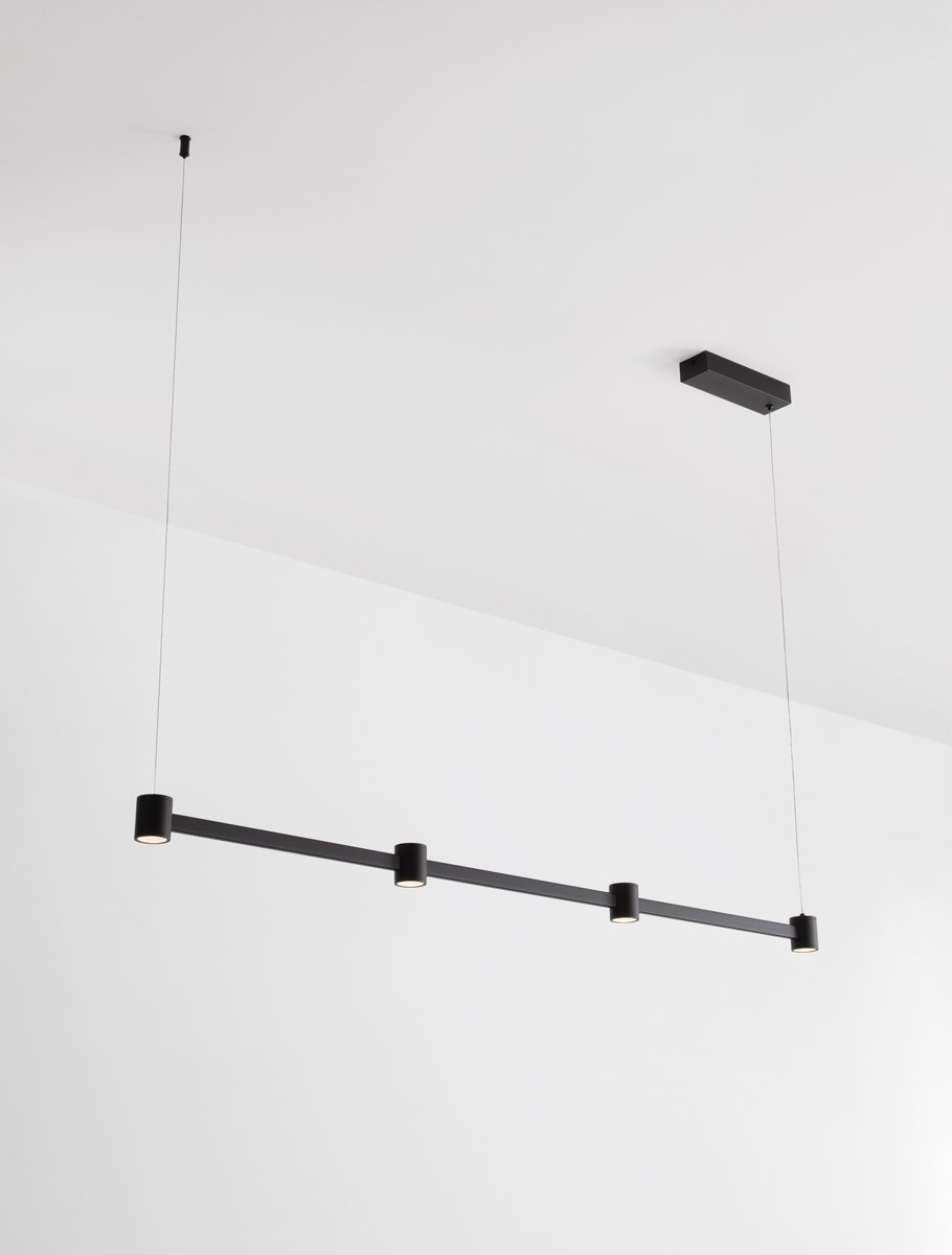 Lampa wisząca Pisco 4xLED 24W w kolorze czarnym, z minimalistycznym, prostokątnym kształtem. Zawieszona na cienkich linkach, z czterema okrągłymi oprawami LED, zamontowana na prostokątnej podsufitce. Tło białe.