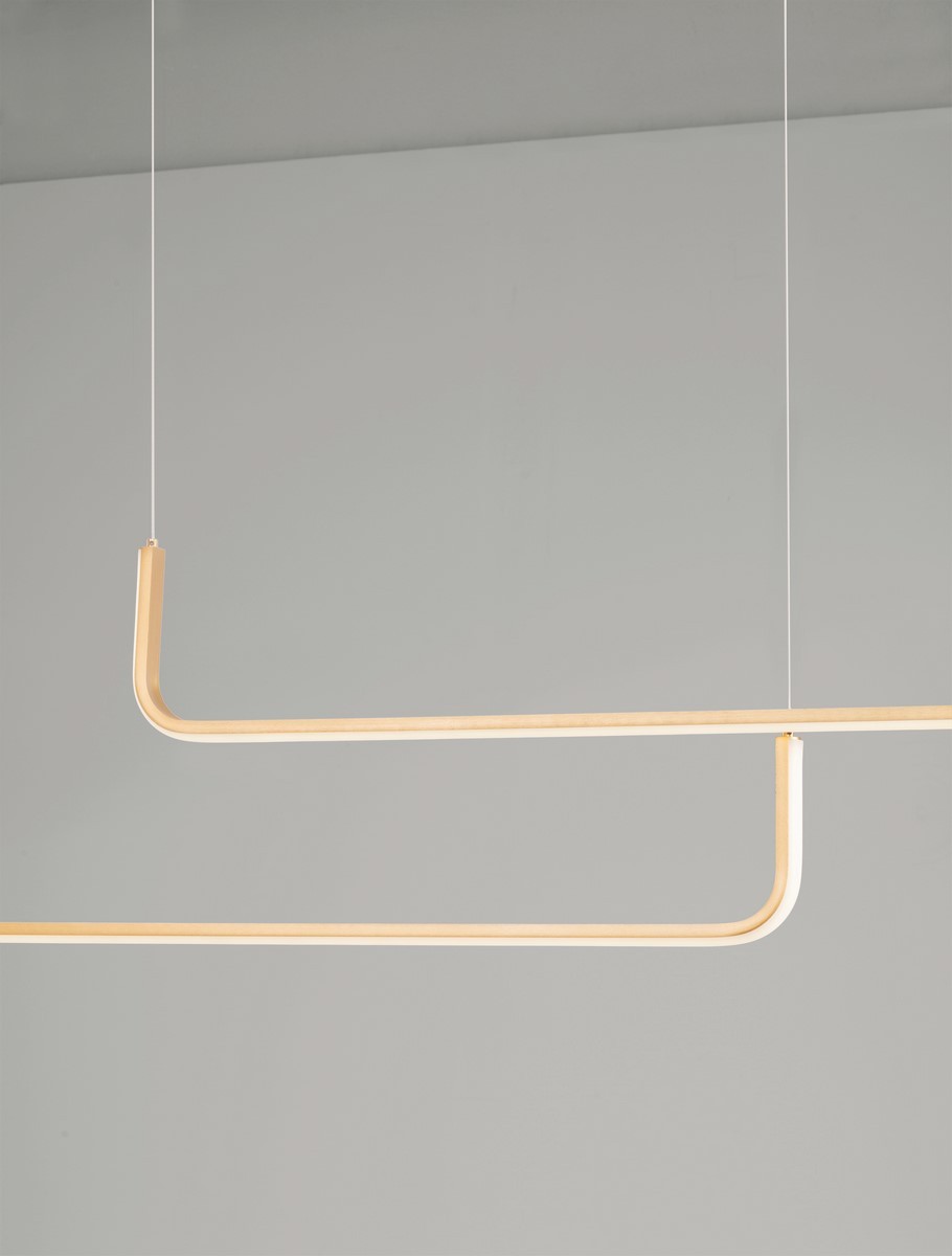 Lampa wisząca Piura w kolorze złotym, z dwoma źródłami światła LED 40W. Konstrukcja składa się z dwóch poziomych, zakrzywionych elementów, zawieszonych na cienkich linkach. Tło jasnoszare, minimalistyczne.