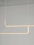 Lampa wisząca Piura w kolorze złotym, z dwoma źródłami światła LED 40W. Konstrukcja składa się z dwóch poziomych, zakrzywionych elementów, zawieszonych na cienkich linkach. Tło jasnoszare, minimalistyczne.