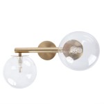 Kinkiet Avola 2xG9 w kolorze złotym z transparentnymi kloszami. Ułożony poziomo, z dwoma okrągłymi kloszami, z widocznymi źródłami światła. Metalowa konstrukcja z matowym wykończeniem. Tło białe.