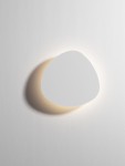 Kinkiet Apure 1xLED 6W w kolorze białym, o asymetrycznym, zaokrąglonym kształcie. Zainstalowany na ścianie, emituje ciepłe światło otaczające. Prosty design idealny do nowoczesnych wnętrz. Tło w jednolitym białym kolorze.