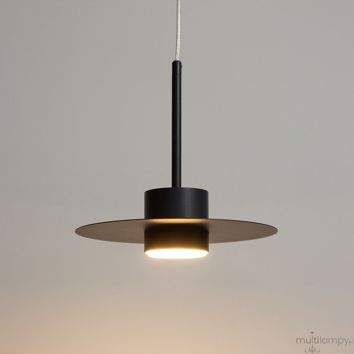 Czarna lampa wisząca Charlie M z jednym źródłem światła GX53, posiadająca cylindryczny korpus i szeroką, okrągłą podstawę. Zawieszona na cienkim przewodzie, z minimalistycznym designem, idealna do nowoczesnych wnętrz.