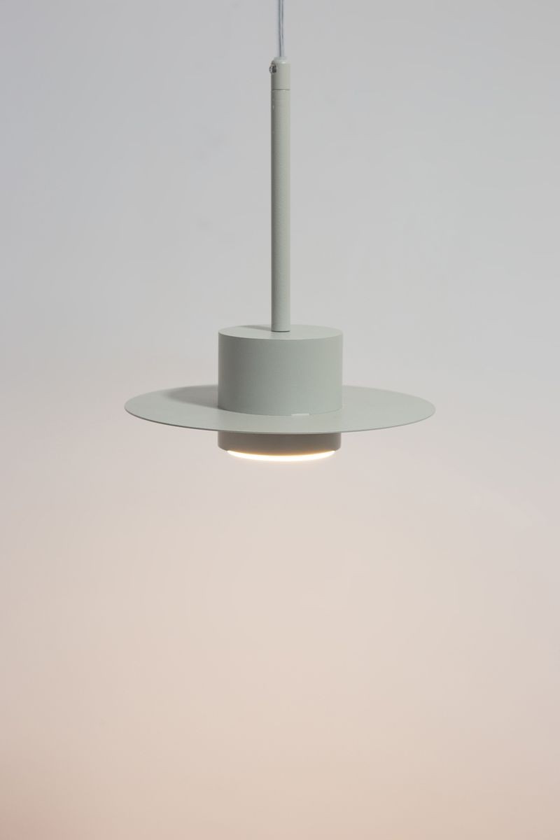 Lampa wisząca Charlie S w kolorze szaro-beżowym, z metalowym kloszem o okrągłym kształcie i płaskim daszkiem. Ujęcie frontalne, zawieszona na cienkim przewodzie. Widoczna oprawa na żarówkę GX53. Proste tło, podkreślające minimalistyczny design.