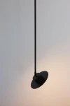 Lampa wisząca Charlie S z jedną oprawą GX53 w kolorze czarnym. Posiada długi, smukły kabel oraz okrągłą, płaską podstawę. Ujęcie z boku, na jasnym tle, pokazuje subtelne oświetlenie. Idealna do nowoczesnych wnętrz.
