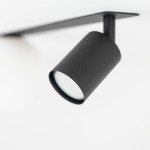 Lampa sufitowa podtynkowa Vox w kolorze czarnym z jednym miejscem na żarówkę GU10 i jednym na G9. W ujęciu zbliżeniowym, z widokiem na cylindryczny klosz oraz montażowy wspornik, umieszczona na białym tle.