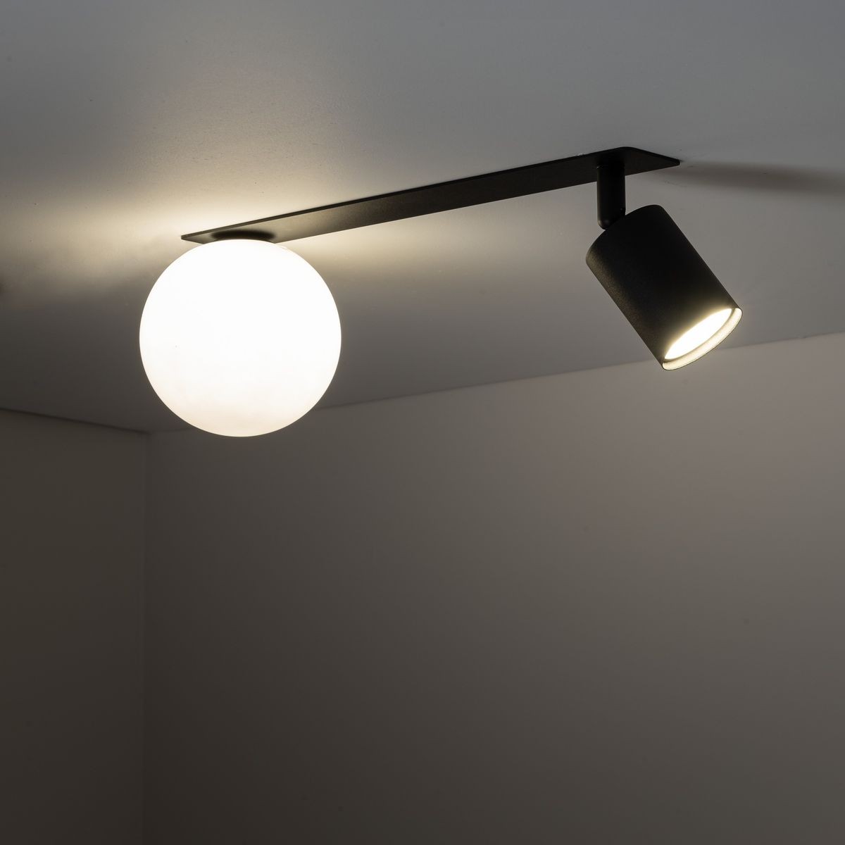 Czarna lampa sufitowa podtynkowa Vox z jednym źródłem światła GU10 i jednym G9. Posiada okrągłą, matową kulę oraz cylindryczny reflektor, zamontowana na prostokątnej podstawie, w ujęciu z góry.