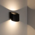 Kinkiet Verto 2xLED 10W IP54 w kolorze czarnym, zamontowany na ścianie, o cylindrycznym kształcie. Emituje ciepłe światło, tworząc na ścianie delikatne cienie. Wykonany z materiału odpornego na wilgoć.