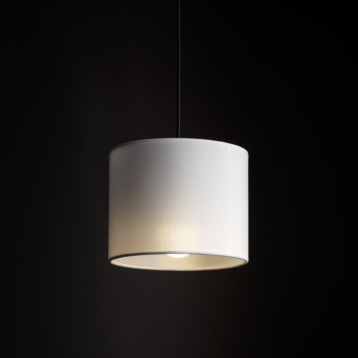 Lampa wisząca Tracer D20 z pojedynczym źródłem światła E27, w białym, teksturowanym kloszu o cylindrycznym kształcie, zawieszona na czarnym kablu. Tło ciemne, podkreślające prosty design lampy.