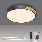 Q-bila lampa sufitowa LED 35W z pilotem, okrągła, czarna z drewnianym detalem. Emituje światło w zakresie 2700K-5000K. Widoczny pilot i ikony funkcji. Lampa zamontowana na jednolitym tle, w pozycji poziomej.