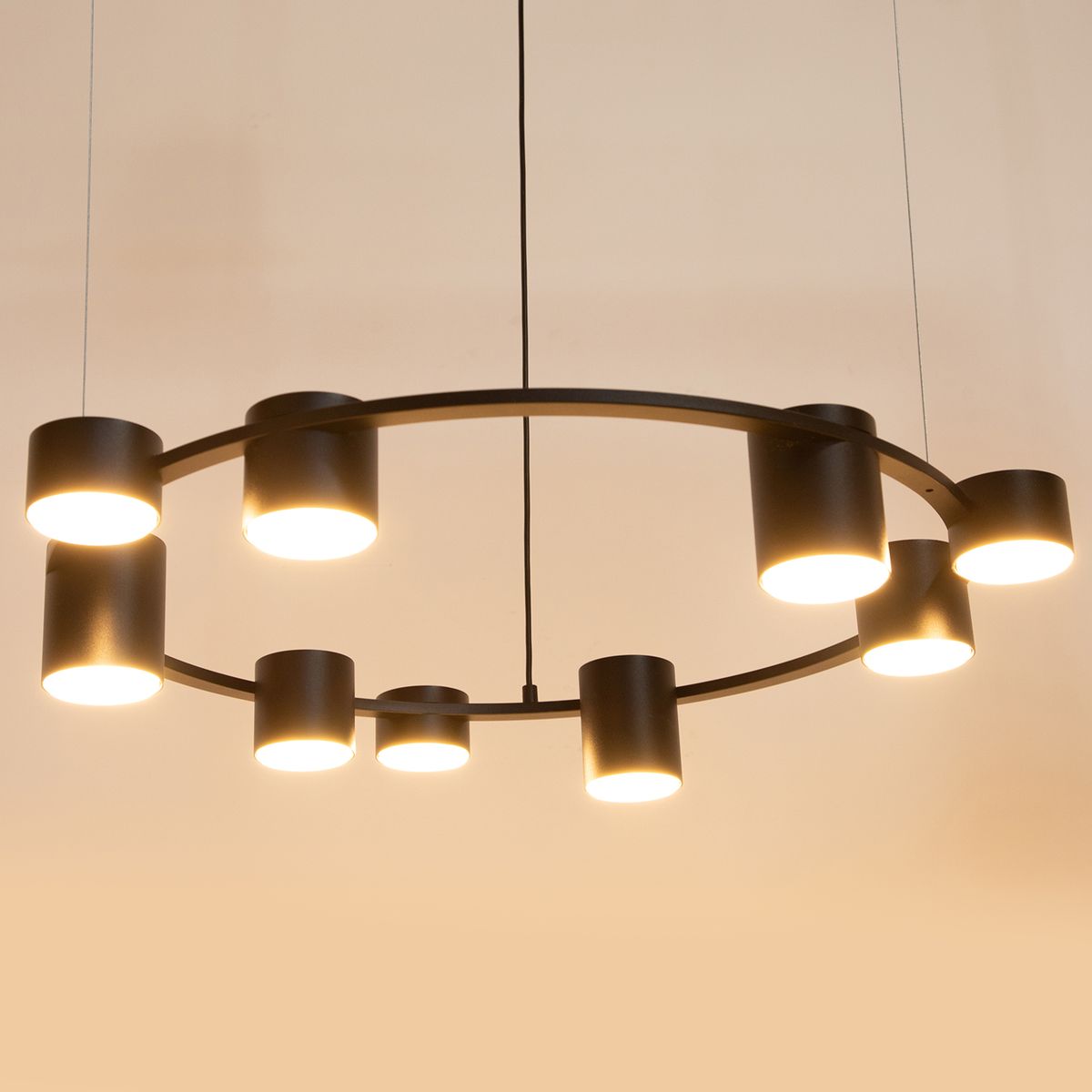 Lampa wisząca Kodo w kolorze czarnym z dziewięcioma oprawami GX53, w formie okręgu. Oświetlenie umieszczone w cylindrycznych kloszach, zawieszona na cienkich linkach. Prosty, nowoczesny design, idealna do wnętrz.