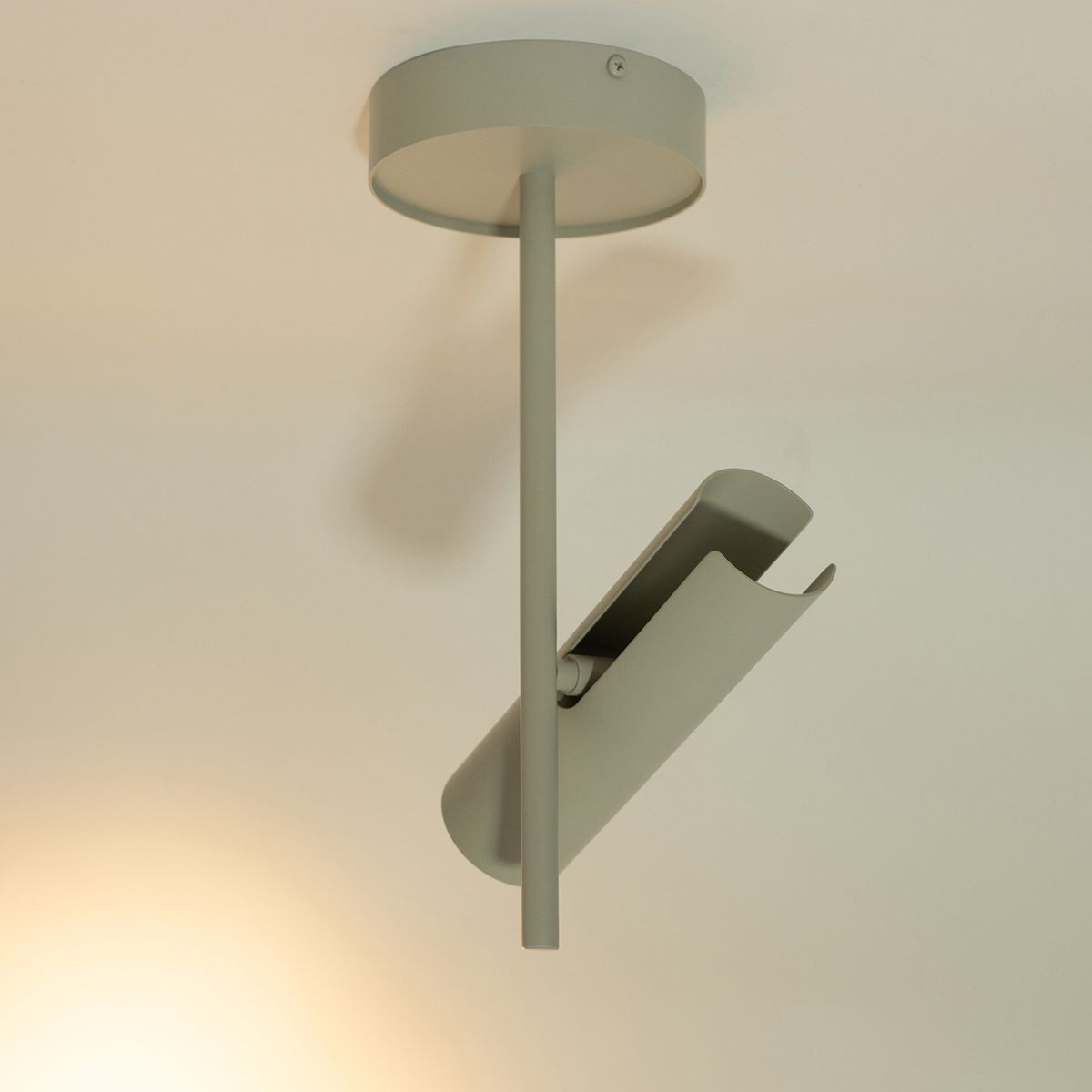 Lampa sufitowa Leda w kolorze szarym beżowym, z jednym miejscem na żarówkę GU10. Ujęcie z dołu, pokazujące prostą, cylindryczną podstawę oraz nachyloną oprawę, podkreślającą minimalistyczny design. Montowana na suficie.