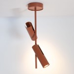 Lampa wisząca Leda, ceglana, z dwoma regulowanymi reflektorami GU10. Stojąca na metalowym stelażu, z widocznym okrągłym mocowaniem sufitowym. Reflektory w kształcie cylindrów, z otwartymi końcami, emitują ciepłe światło, tworząc nowoczesny akcent.