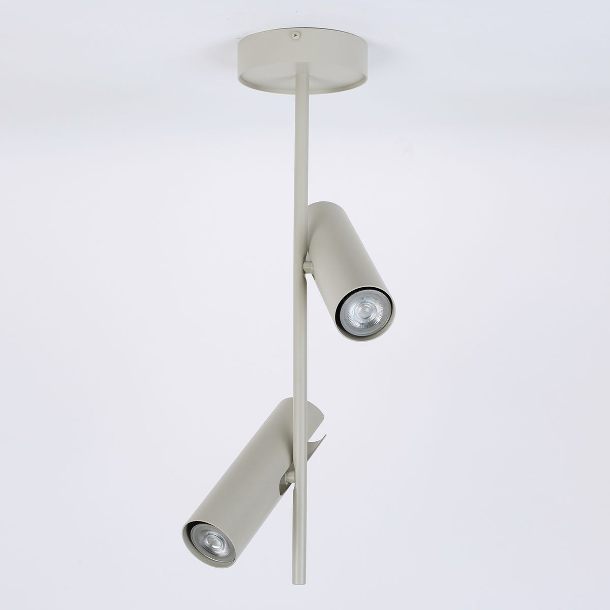 Lampa wisząca Leda w kolorze szarym beżowym z dwoma reflektorami GU10. Produkt zawieszony na prostym, okrągłym mocowaniu, z możliwością regulacji kierunku światła. Tło białe, minimalistyczne.