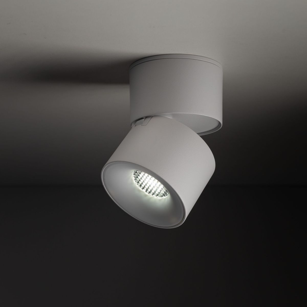 Lampa sufitowa Spark w kolorze białym, z jedną głowicą LED 10W, umieszczona na okrągłej podstawie. Ujęcie z boku, pokazujące kąt obrotu oraz fakturę obudowy. Akcentuje nowoczesny design i funkcjonalność oświetlenia.