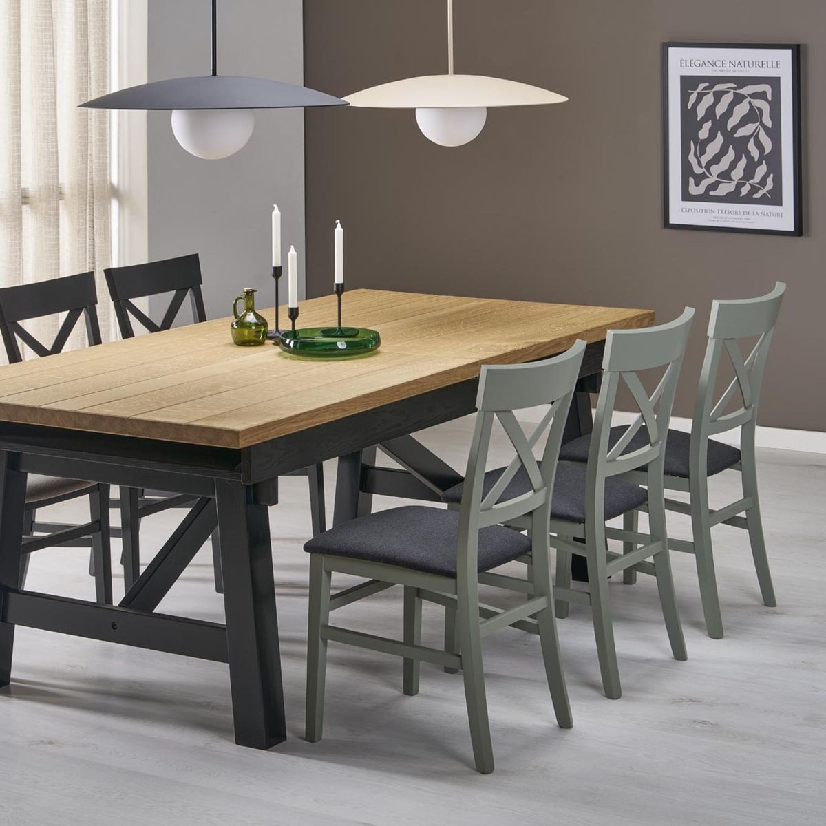Beżowa lampa wisząca Slate 1xE27 zawieszona nad drewnianym stołem, w otoczeniu czterech krzeseł w odcieniach szarości i ciemnego drewna. Tło w neutralnych kolorach, z dekoracjami na stole i obrazem na ścianie.