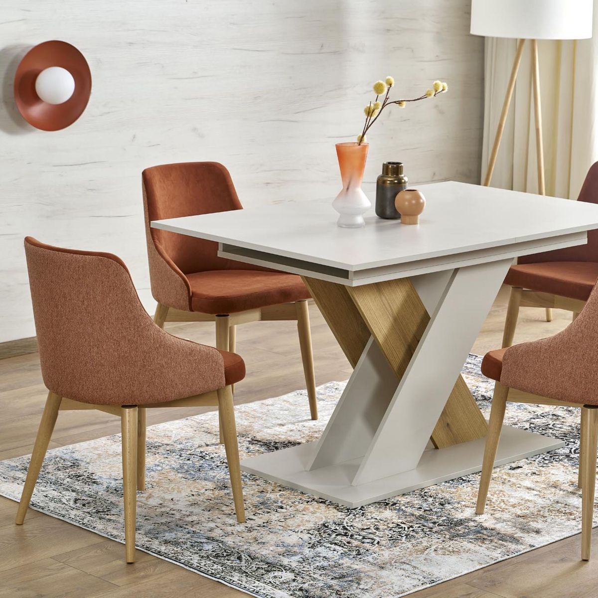 Ceglasty kinkiet Slate 1xG9 zamontowany na ścianie, w tle nowoczesny stół z białym blatem i drewnianą podstawą, otoczony czerwonymi krzesłami tapicerowanymi. Obok dekoracyjne akcesoria na stole oraz dywan w jasnych kolorach.