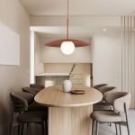 Lampa wisząca Slate z ceglastym kloszem i okrągłą, białą żarówką, zawieszona nad owalnym drewnianym stołem w jasnym wnętrzu. W tle widoczne krzesła tapicerowane w neutralnym kolorze oraz minimalistyczna aranżacja kuchni.