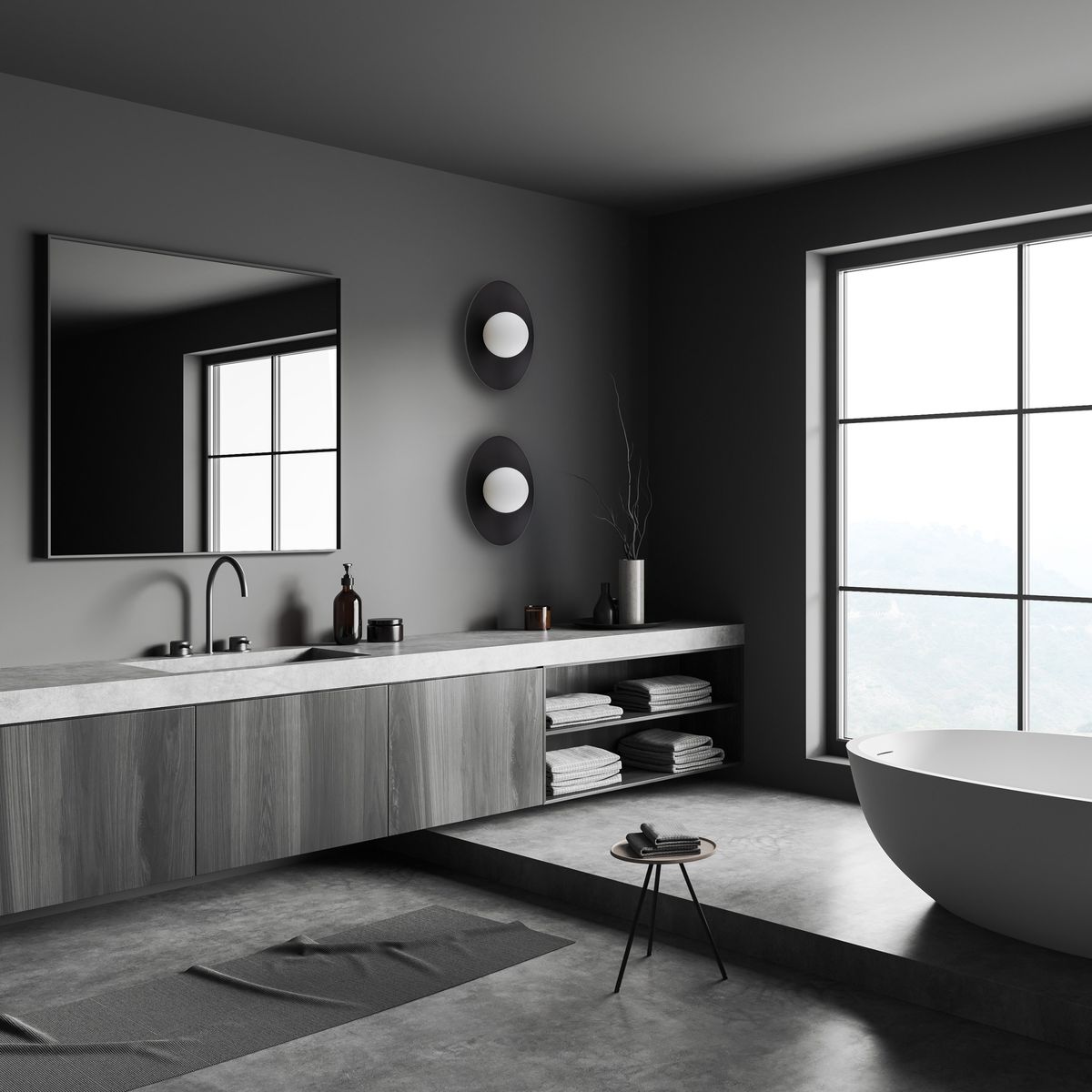 Kinkiet Slate 1xG9 w kolorze czarnym, okrągły, zamontowany na ścianie w nowoczesnej łazience. W tle widoczny dużą lustro oraz minimalistyczne meble z szarym blatem. Dodatki w stonowanej kolorystyce na tle szarej ściany.