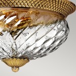 Plafon w stylu vintage, wykonany z przezroczystego szkła z wypukłymi wzorami, z postarzanym mosiężnym wykończeniem. Ujęcie z góry, ukazujące detale klosza oraz dekoracyjny element montażowy. Idealny do wnętrz w stylu klasycznym.