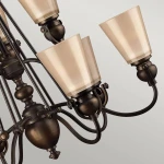 Lampa wisząca Mayflower z dziewięcioma kloszami E27 w postarzanym brązie. Klosze mają kształt stożkowaty w odcieniu beżowym, zamocowane na eleganckim, metalowym stelażu. Kąt ujęcia z boku ukazuje szczegóły konstrukcji i wykończenia.