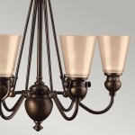 Lampa wisząca Mayflower w postarzanym brązie z sześcioma oprawami na żarówki E27. Posiada szklane klosze w kształcie stożków, metalową konstrukcję z dekoracyjnymi detalami, zawieszoną na smukłym stelażu.