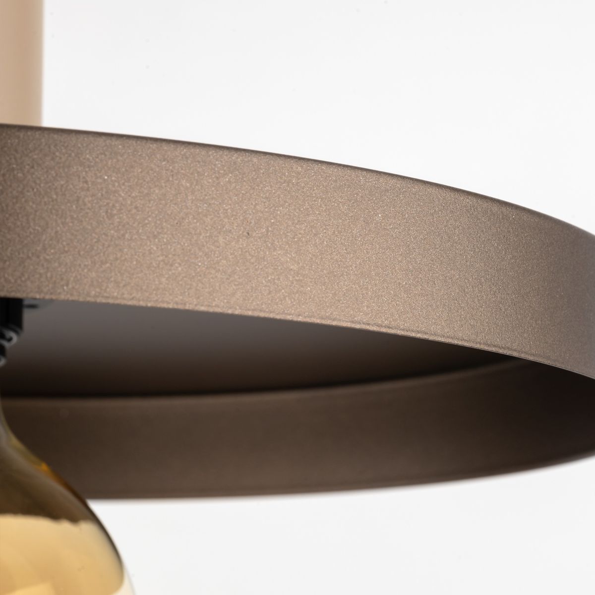 Beżowa lampa wisząca Sila D30 z jednym gniazdem E27, widok na metalowy klosz o matowej fakturze i brązowym wykończeniu, z lekko zaokrąglonym kształtem. Klosz wisi na czarnej oprawie, na białym tle.