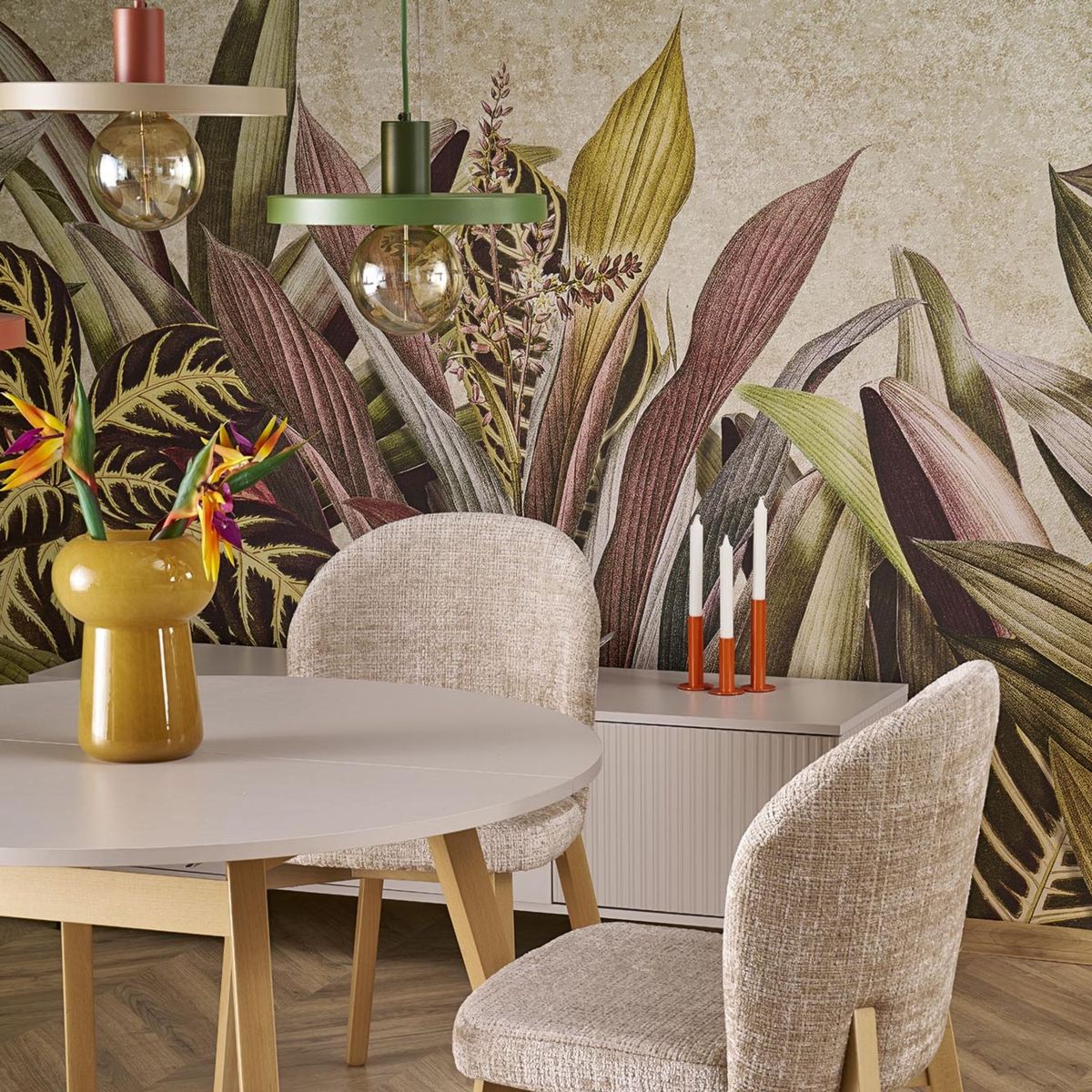 Lampa wisząca Sila D30 w kolorze zielonym z oprawą na jedną żarówkę E27, zawieszona nad okrągłym stołem. W tle widoczna roślinna tapeta oraz dekoracje na stole, w tym wazon i świeczki.