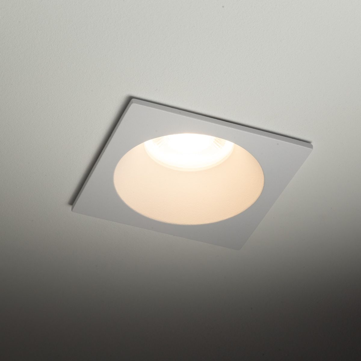 Oprawa sufitowa Prisma 1xGU10 w kolorze białym, montowana w zabudowie. Kwadratowy kształt z okrągłym otworem, z widoczną żarówką w środku. Wykończenie matowe, odpowiednia do użytku w pomieszczeniach z klasą ochrony IP64.