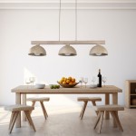 Lampa wisząca Oslo 3xE27 w jasnym drewnie z beżowymi kloszami, zawieszona nad drewnianym stołem. W tle widoczne owoce w misce, kieliszki oraz butelka wina. Proste tło podkreśla nowoczesny design.