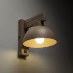 Kinkiet Oslo 1xE27 w jasnym drewnie i beżowym kolorze, z metalową kloszem w kształcie półkuli. Ujęcie z boku, montowany na ścianie, z widocznym włącznikiem. Oświetlenie emituje ciepłe światło, idealne do aranżacji wnętrz.