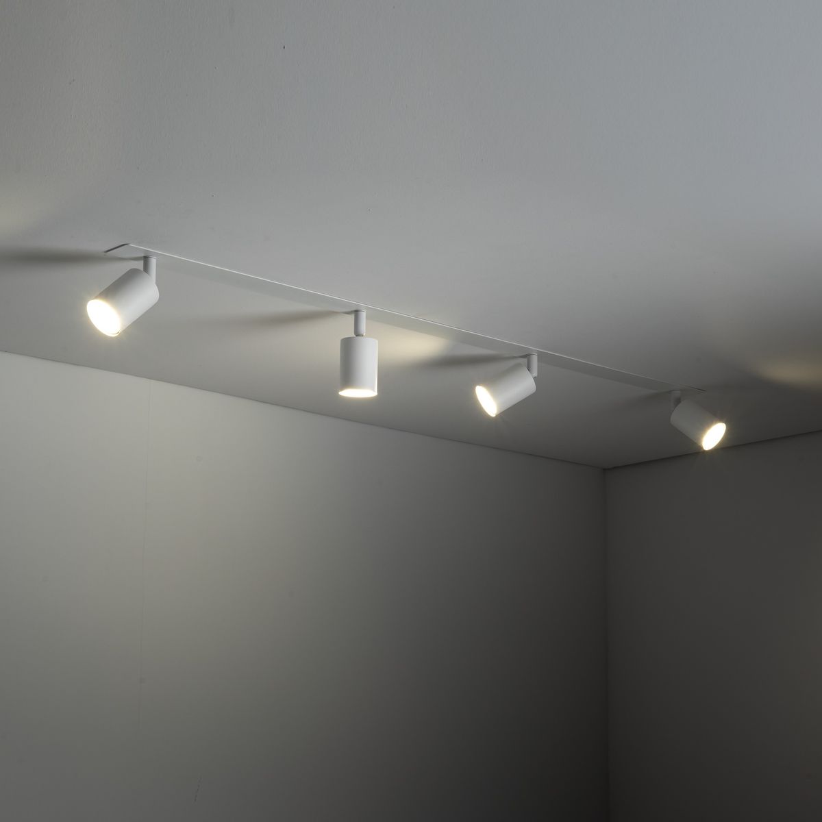 Lampa sufitowa podtynkowa Nex w kolorze białym, z czterema oprawami GU10. Ujęcie z boku, z lampami skierowanymi w różne strony. Prosty, minimalistyczny design, montowana na suficie, idealna do nowoczesnych wnętrz.