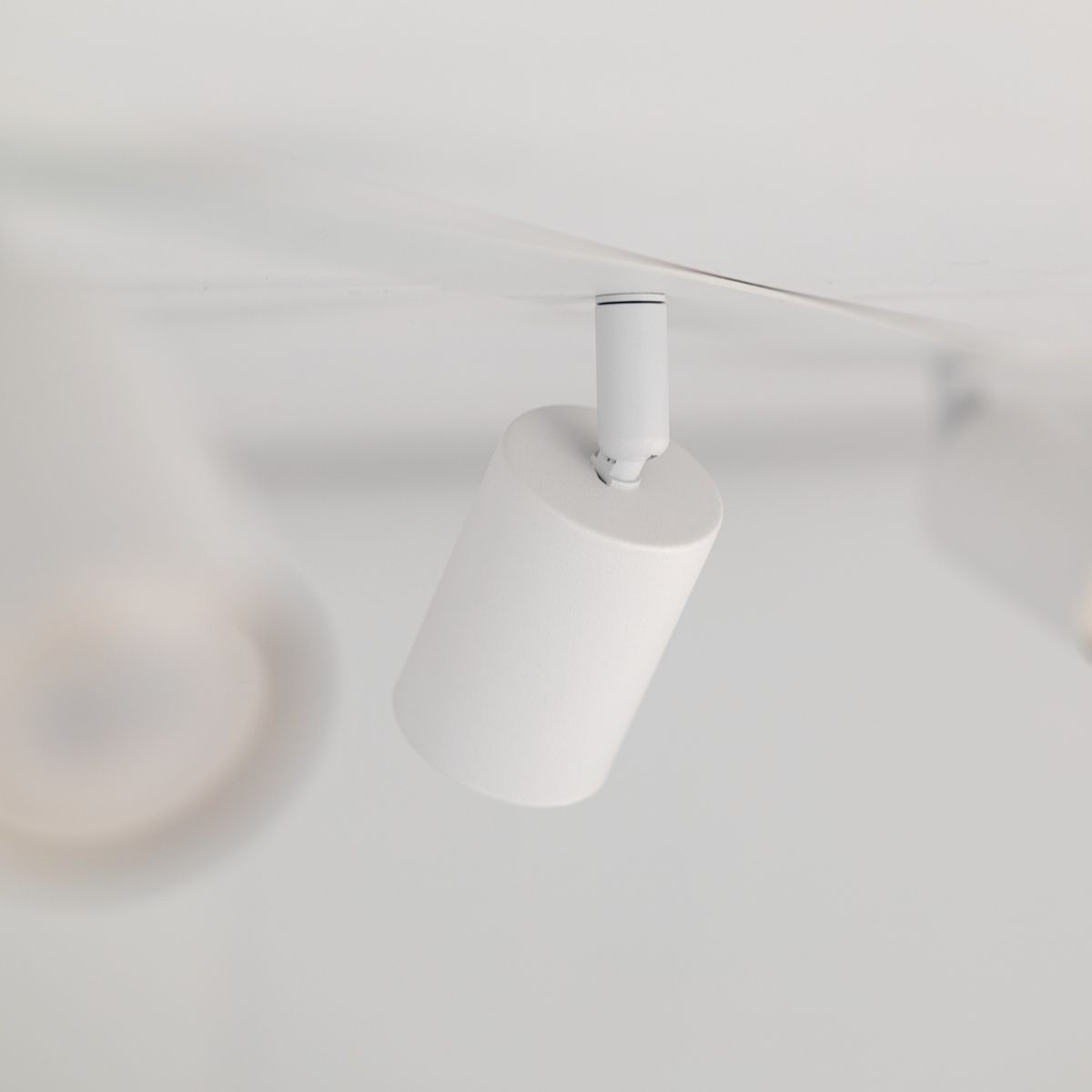 Lampa sufitowa podtynkowa Nex w kolorze białym z miejscem na cztery żarówki GU10. Produkt widoczny z góry, z cylindrycznym kloszem, zamontowany w suficie. Prosta forma, brak dodatkowych zdobień.
