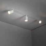 Lampa sufitowa podtynkowa Nex, kolor biały, z trzema oprawami na żarówki GU10. Zamontowana na płaskiej, prostokątnej podstawie, z widocznymi reflektorami w kształcie cylindrów. Oświetlenie skierowane w dół, na jednolitym tle.