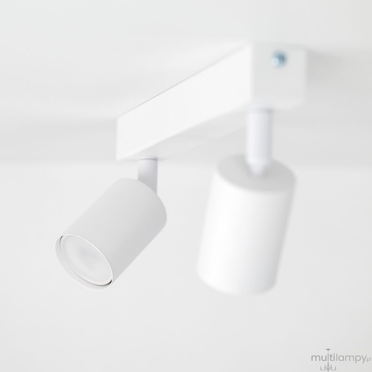 Lampa sufitowa Nex w kolorze białym z dwoma punktami świetlnymi typu GU10. Ujęcie z boku, pokazujące cylindryczne klosze i prostokątną podstawę. Elementy zamontowane pod sufitem, minimalistyczny design.