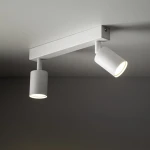 Lampa sufitowa Nex w kolorze białym z dwoma reflektorami typu GU10. Reflektory mają cylindryczny kształt i są zamocowane na prostokątnej podstawie. Ujęcie z dołu, pokazujące oświetlenie skierowane w dół.