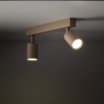 Lampa sufitowa spot Nex w kolorze beżowym z dwoma regulowanymi punktami świetlnymi, zamontowana na prostokątnej podstawie. Kąt ujęcia z dołu, ukazujący detale wykończenia oraz emitowane światło.