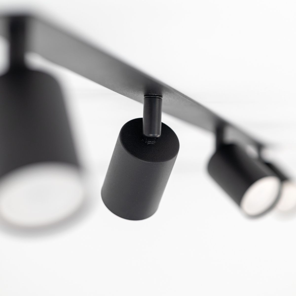 Lampa sufitowa podtynkowa Nex z czterema punktami świetlnymi GU10. Czarna konstrukcja z cylindrycznymi kloszami, zamontowana na prostokątnej podstawie. Ujęcie z dołu, ukazujące detale i fakturę materiału.