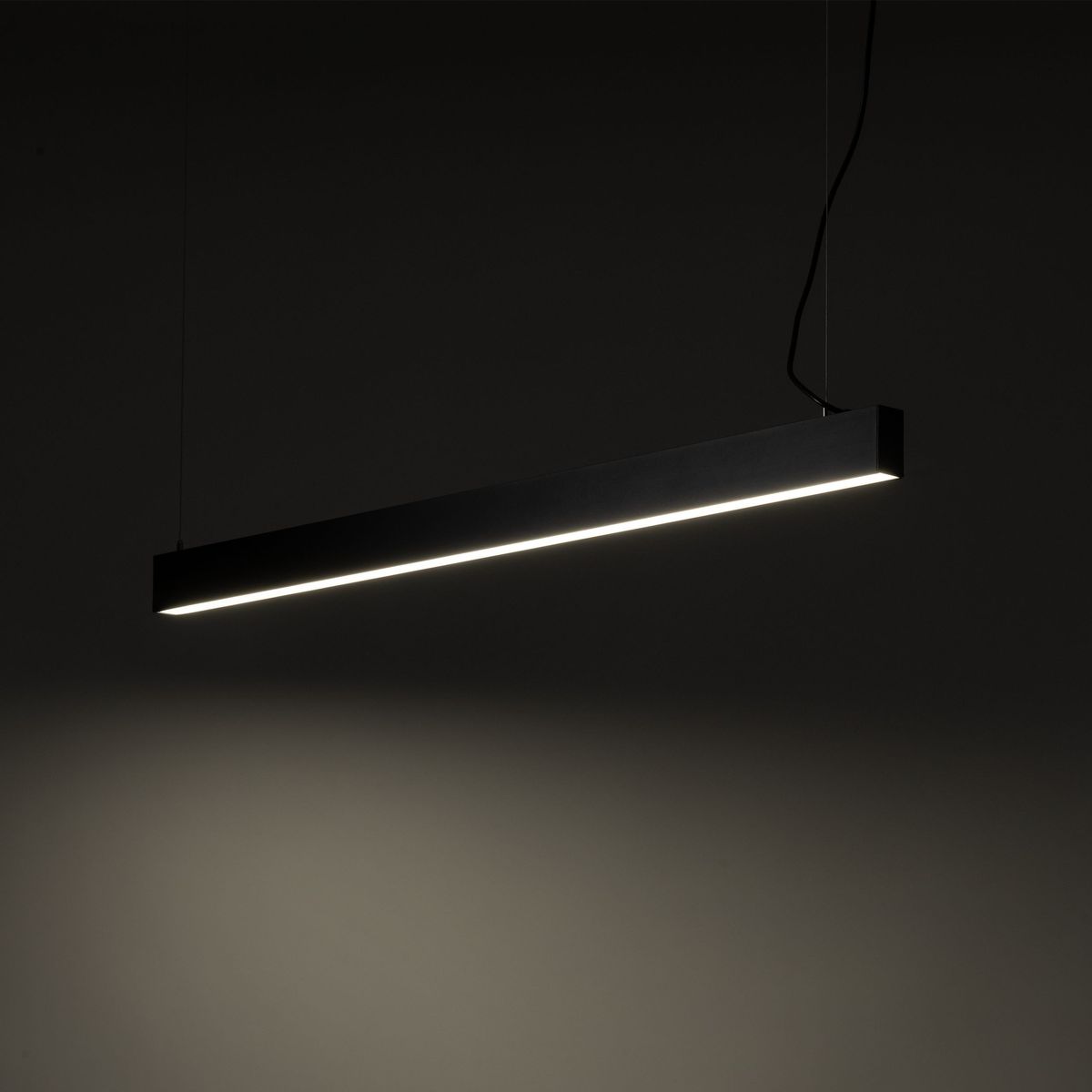 Luxe lampa wisząca 1xLED CCT w kolorze czarnym, o prostokątnym, minimalistycznym kształcie, zawieszona na cienkich linkach. Emituje ciepłe światło LED, idealna do nowoczesnych wnętrz. Tło ciemne, podkreślające elegancję lampy.