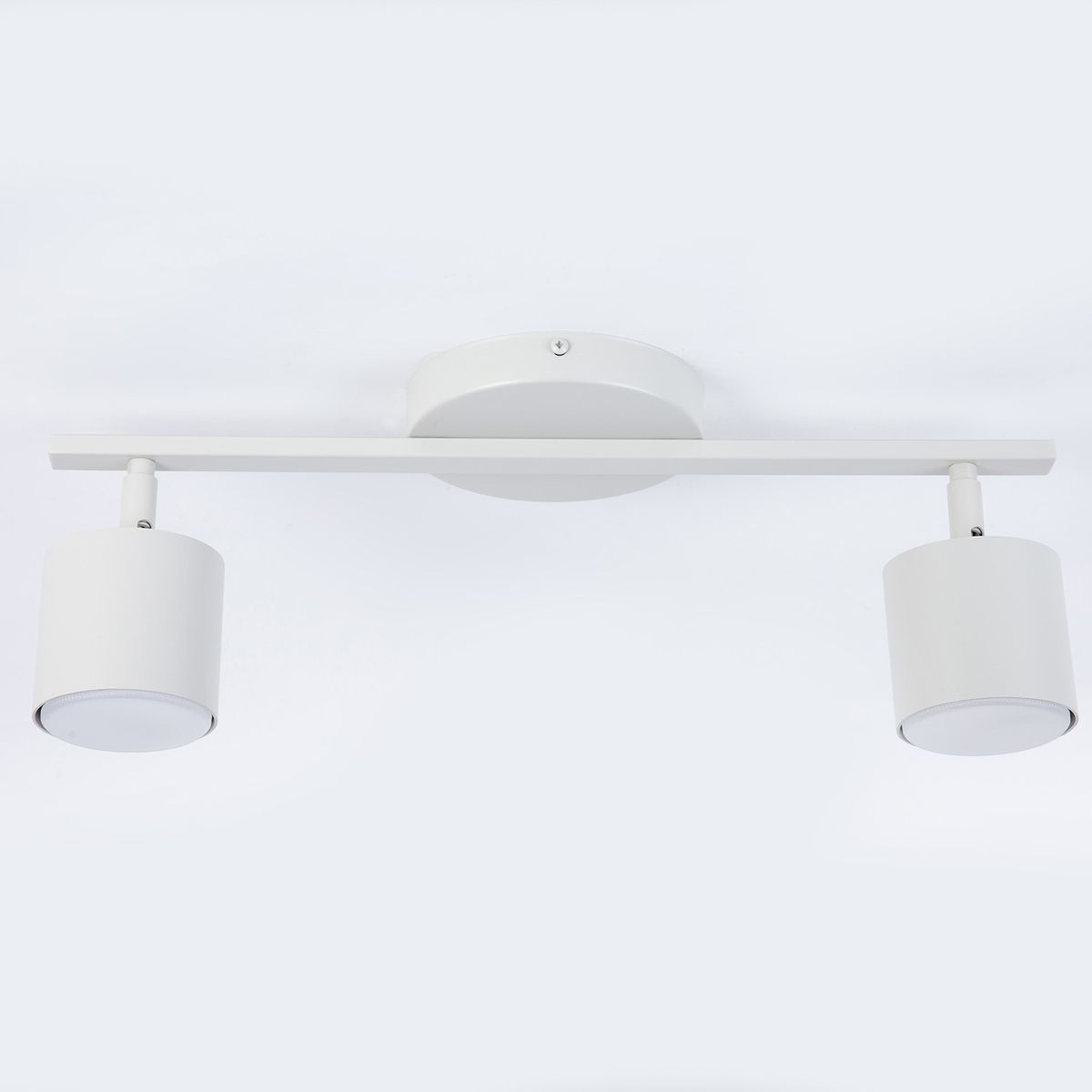 Lampa sufitowa Mila z dwoma reflektorami w kolorze szarym beżowym. Uchwyt w formie prostokątnej listwy, cylindryczne klosze z białym wykończeniem. Zawieszona na suficie, w prostym, nowoczesnym stylu.