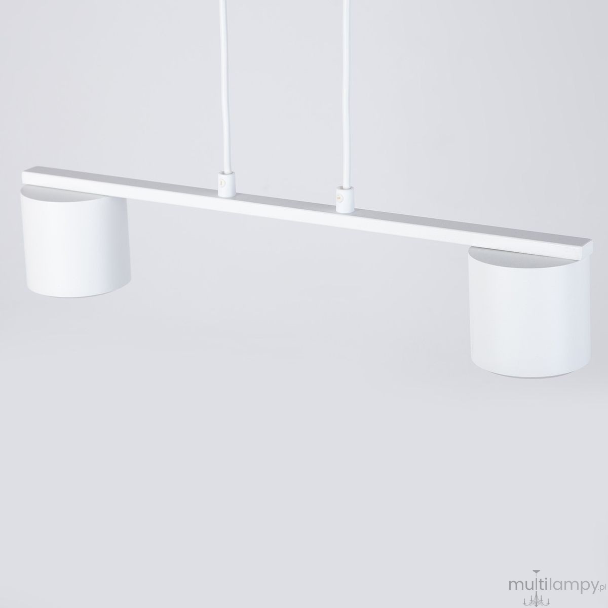 Lampa wisząca Mila w kolorze białym z dwoma oprawami na żarówki GX53. Prosta, minimalistyczna konstrukcja z poziomą belką i dwiema cylindrycznymi kloszami. Zawieszona na dwóch kablach na jednolitym tle.