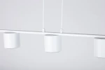Biała lampa wisząca Mila z trzema oprawami GX53. Wzór minimalistyczny, cylindryczne klosze zawieszone na prostej listwie. Produkt widoczny z przodu, zawieszony na cienkich przewodach, na jasnym tle.