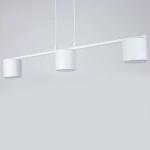 Lampa wisząca Mila w kolorze białym, z trzema cylindrycznymi kloszami na żarówki GX53. Produkt zawieszony na dwóch linkach, z minimalistycznym designem, idealny do nowoczesnych wnętrz. Tło w jednolitym, jasnym kolorze.