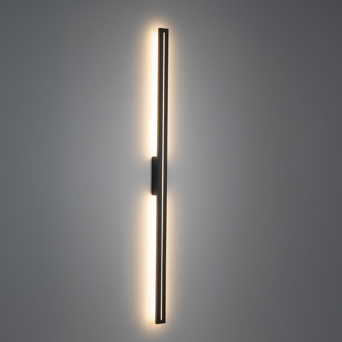 Kinkiet Linea M 1xLED 30W IP65 w kolorze szarym, w wąskim, pionowym kształcie. Zamontowany na ścianie, emituje ciepłe światło z obu stron. Minimalistyczny design, idealny do nowoczesnych wnętrz.