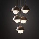 Lampa wisząca Bono z pięcioma kloszami w kształcie półkul, w kolorze matowej szarości, z białymi szklanymi kulami. Zawieszona na cienkich linkach, w minimalistycznym stylu, na ciemnym tle. Idealna do nowoczesnych wnętrz.
