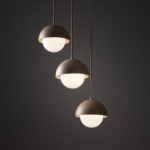 Lampa wisząca Bono z trzema kulistymi kloszami w kolorze beżowym, z białymi, szklanymi lampkami. Klosze mają półkolisty kształt i są zawieszone na cienkich przewodach, tworząc nowoczesny efekt wizualny na ciemnym tle.