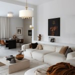 Lampa wisząca Abu Dhabi 5-punktowa w kolorze złotym i białym, z okrągłym kloszem, zawieszona w nowoczesnym wnętrzu. W tle widoczna jasna sofa, stół jadalny oraz dekoracje na ścianach. Wnętrze utrzymane w stonowanej kolorystyce.
